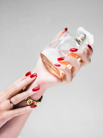 Lola’s red nails around a bottle of perfume, getting ready for an escort date in London
