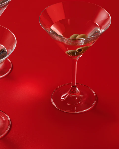 A martini with olives on a glossy red table: dinner date escort in Chelsea and Kensington