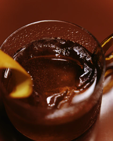 A red cocktail with an orange twist on a glossy red table: dinner date escort in Chelsea and Mayfair